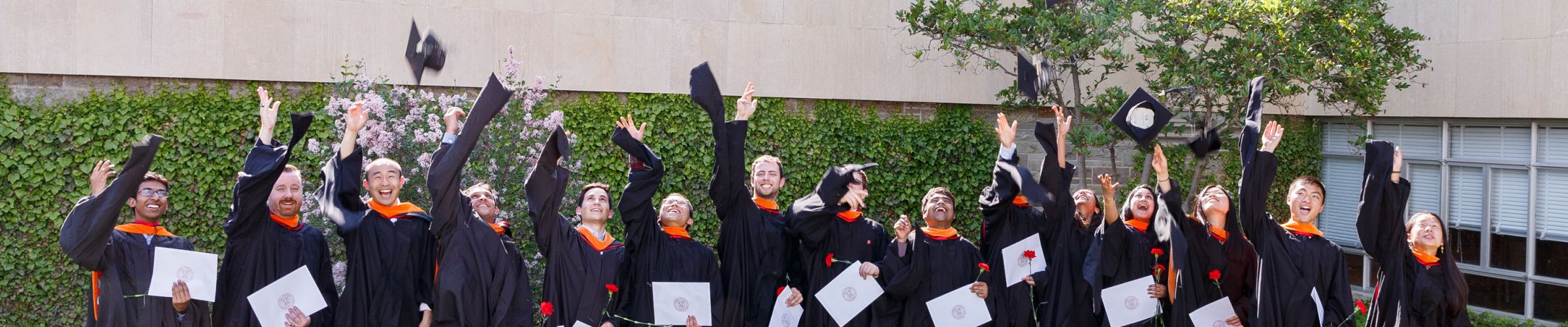 masters students throwing graduation caps in the air