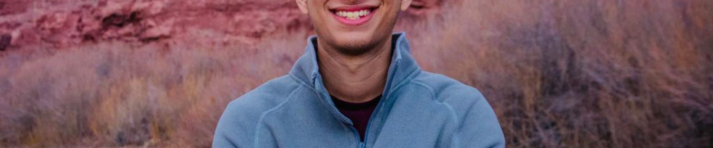 A color photo of a man smiling for a photo outside