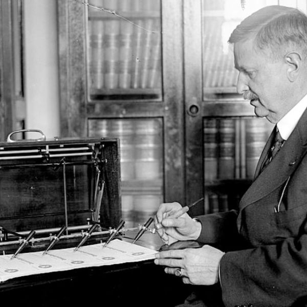 Provided In 1918, J.L. Summers operates a check signing machine in the treasury department, demonstrating an earlier technology to automate signatures.