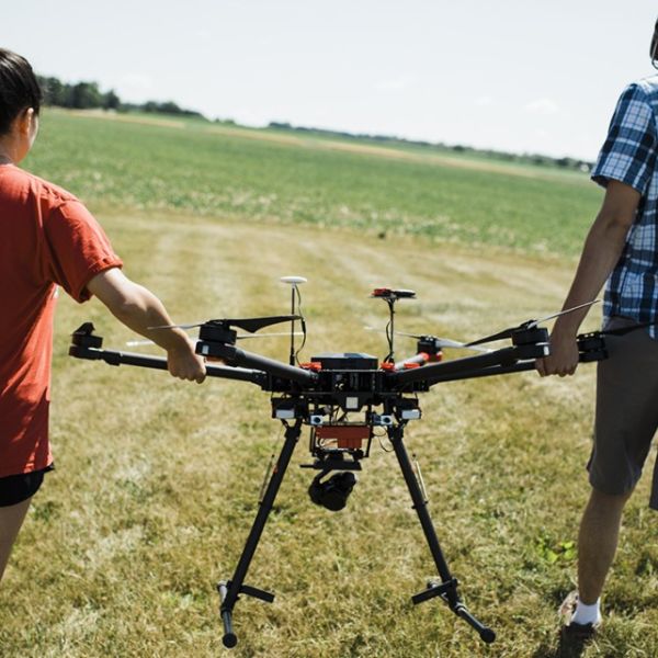 people walking in field holding drone