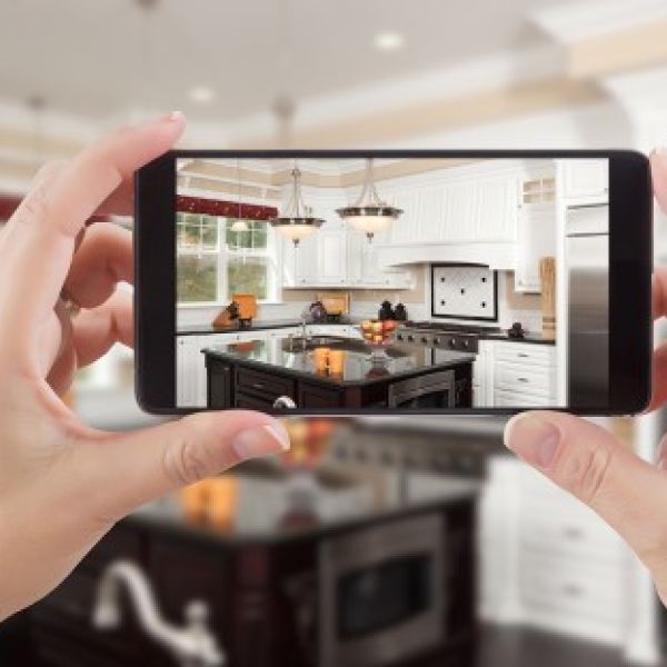 A color photo of hands holding a phone looking at an image of the room they are in