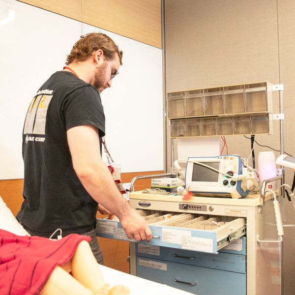 A color photo showing two people using a robotic medical crash cart.