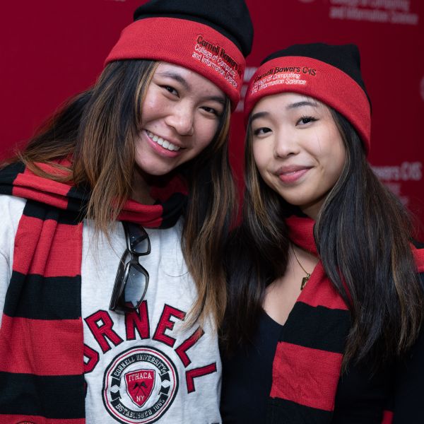 A color photo of two woman smiling for a photo with Cornell clothing