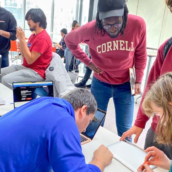 A provided photo showing consultants at the Fall 2023 tech repair fair help visitors fix their malfunctioning devices.