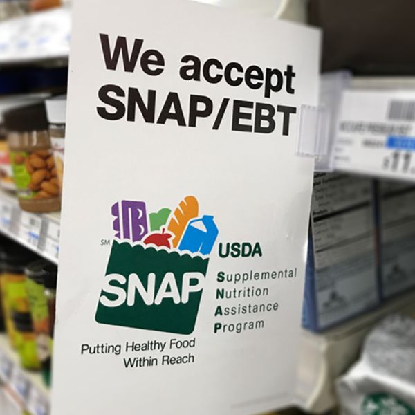 A color photo showing a grocery store shelf with a sign promoting the "SNAP" program - Credit: Shutterstock