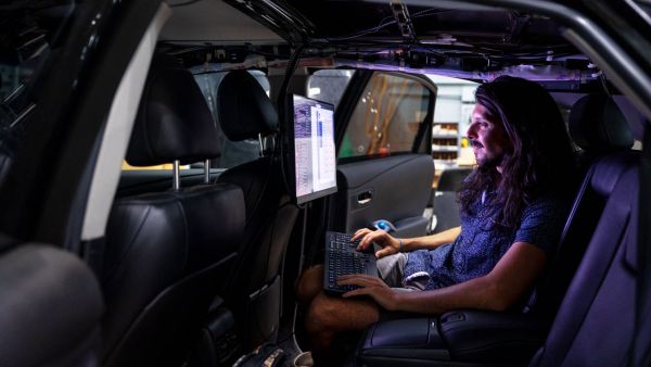 Carlos Diaz-Ruiz, a doctoral student, drives the data collection car and demonstrates some of the data collection techniques the autonomous vehicle researchers use to create their algorithms. A student sits in backseat of car and looks at data collected and demonstrates some of the data collection techniques the autonomous vehicle researchers use to create their algorithms.
