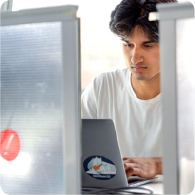 A color photo of a man working on a computer