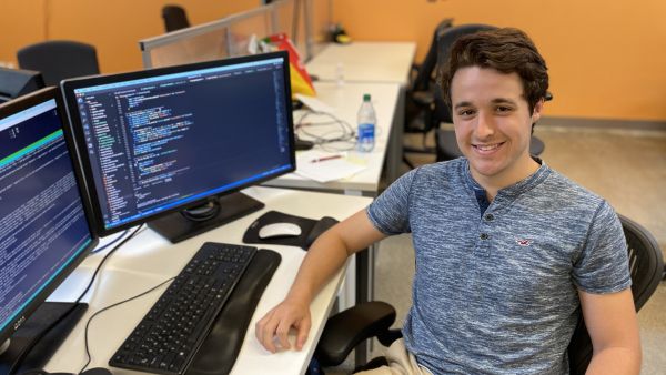 A color photo of a man sitting and smiling for a photo