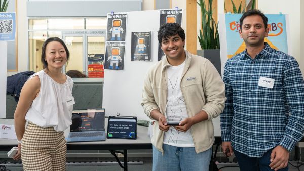 Credit: Rachel Philipson A color photo showing a woman and two men in front of their project at BOOM 2025