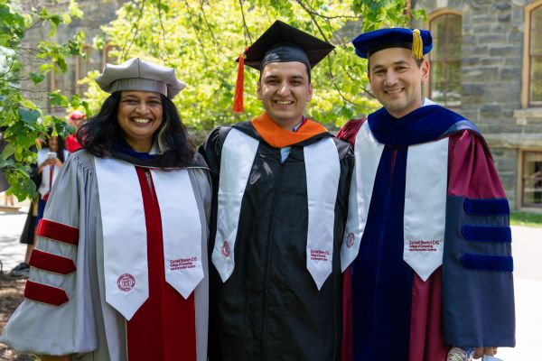 A color photo showing 3 people at the Cornell University commencement