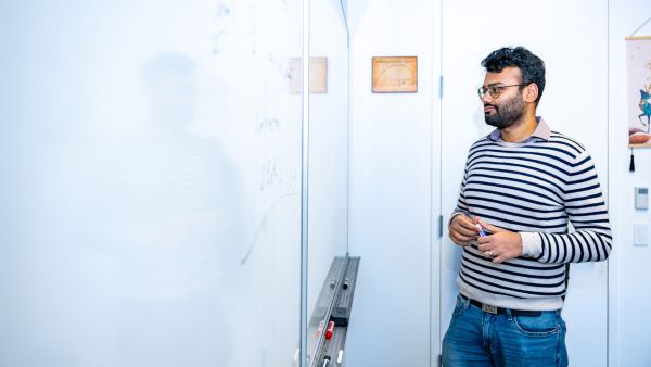 A color photo of a man working on a dry-erase board