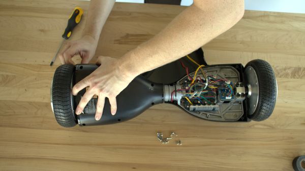 A color photo showing hands disassembling a hoverboard.