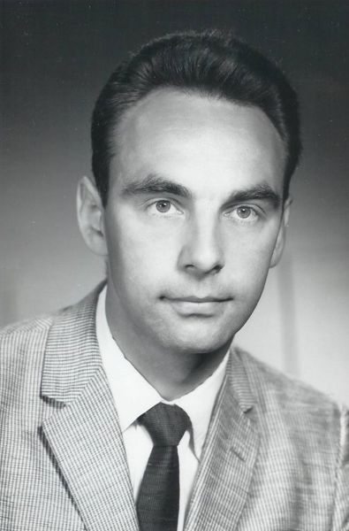 black and white headshot, man in suit looking at camera