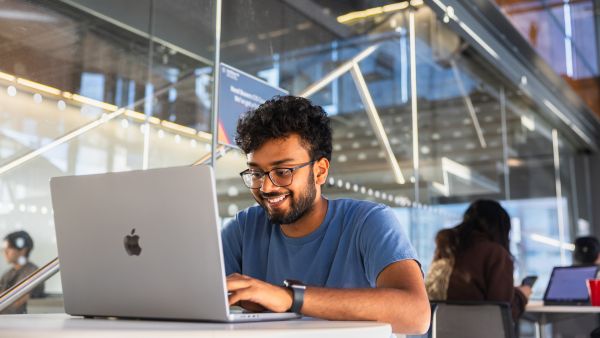 A color photo showing a man working on a computer