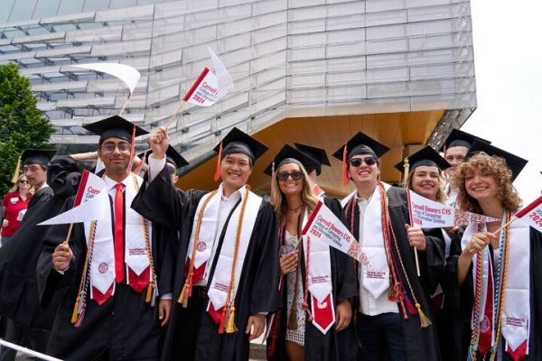 A color photo showing graduates celebrating in front of Gates Hall